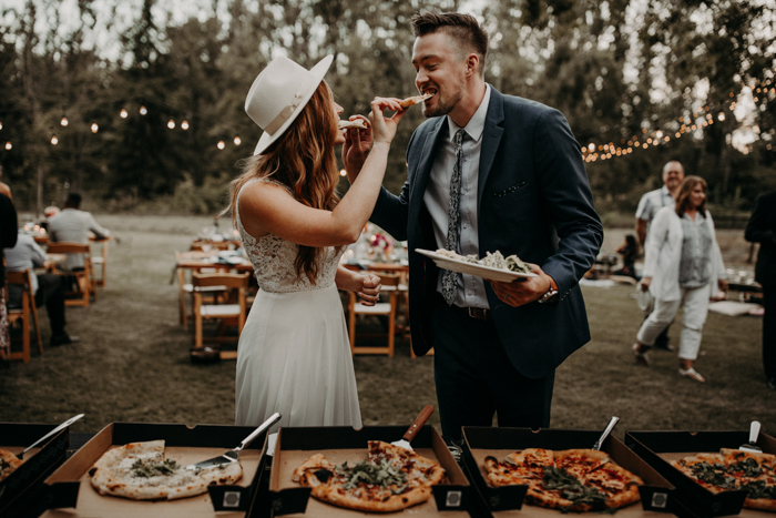 bride and groom feeding each other pizza